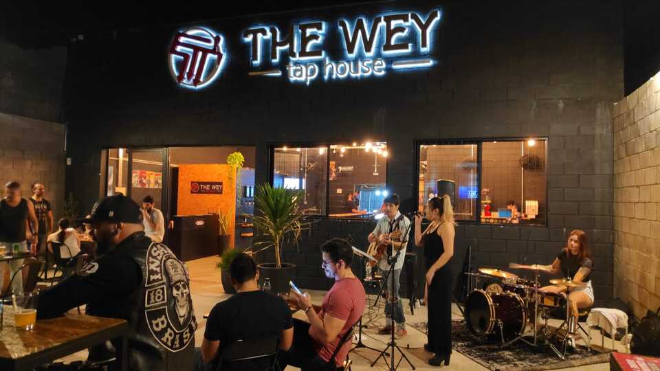 área externa do bar, com pessoas sentadas e banda tocando